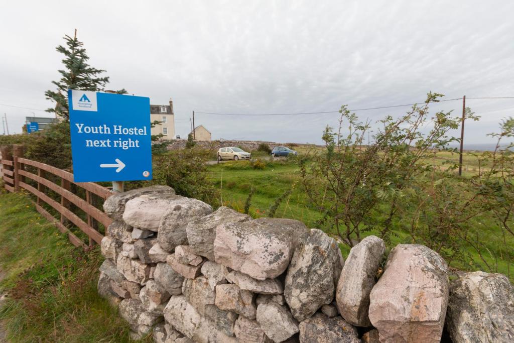 a sign on top of a stone wall at Durness Youth Hostel in Durness