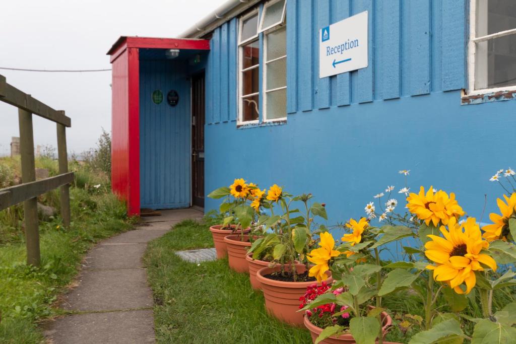 a blue building with flowers inront of it at Durness Youth Hostel in Durness