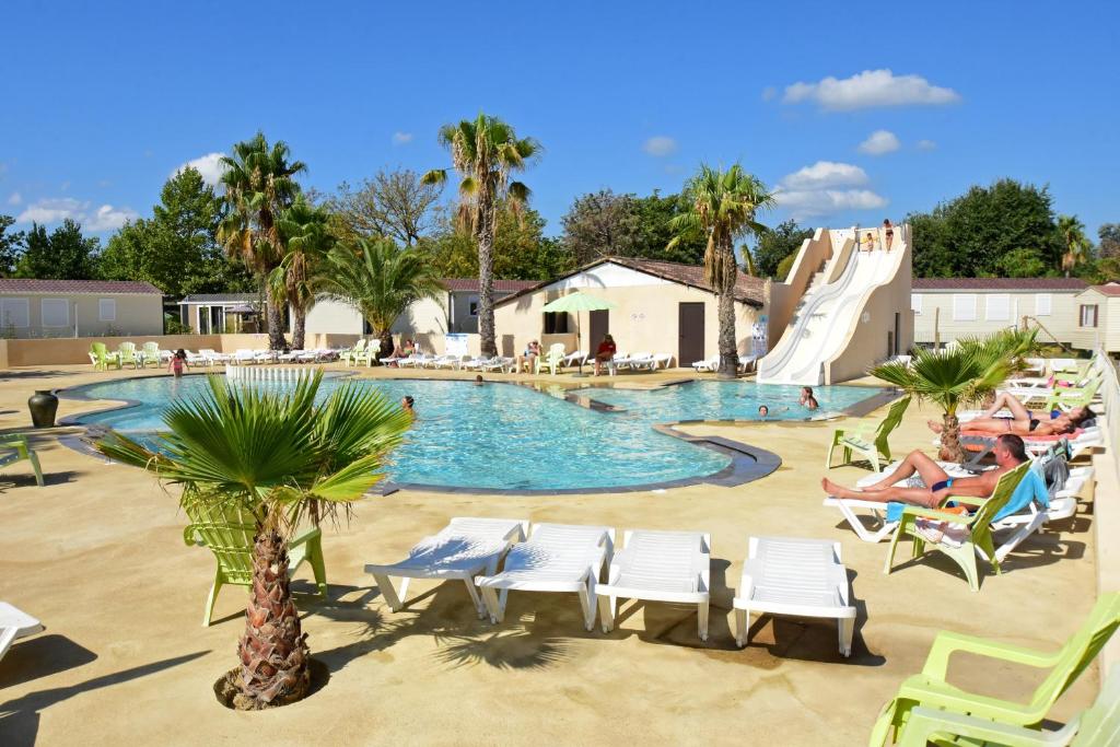 einen Pool mit Stühlen und einer Rutsche in einem Resort in der Unterkunft Camping Domaine Du Golfe De Saint Tropez in Grimaud