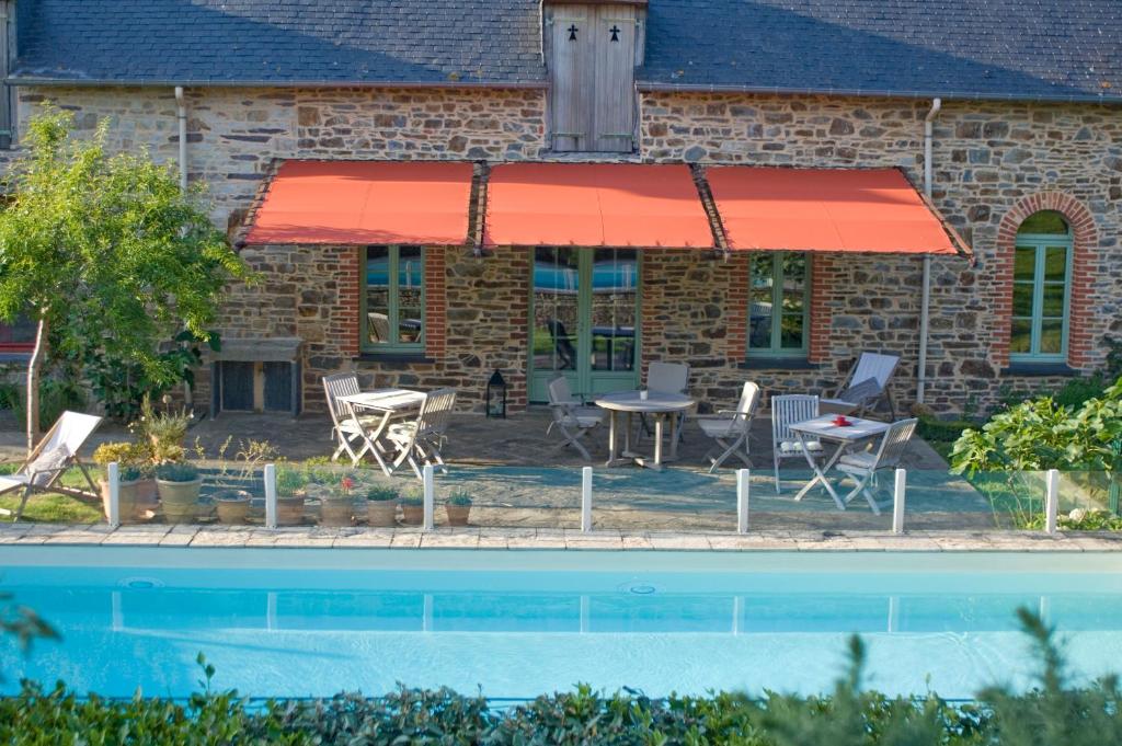 a house with a red awning next to a pool at Tillac Chambres d'hôtes in Pléchâtel