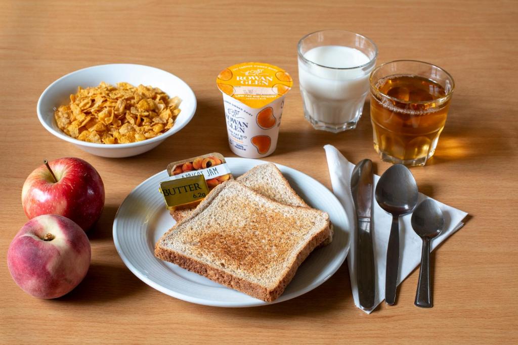 a table with a plate of toast and apples and a glass of milk at Durness Youth Hostel in Durness