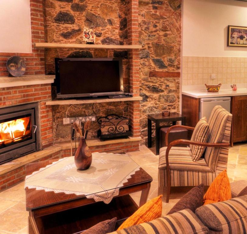 a living room with a fireplace and a tv at Archontiko I Misirlou in Kalopanayiotis