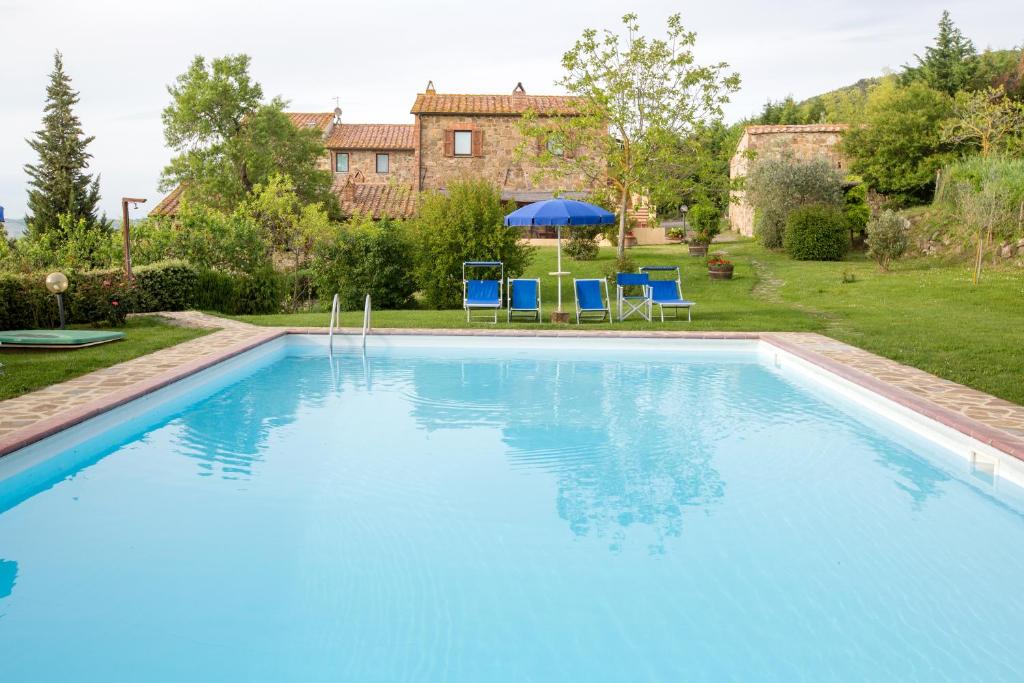 una gran piscina con sillas azules y sombrilla en Podere Il Tigliolo en Castiglione dʼOrcia