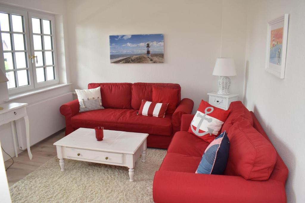 a living room with a red couch and a table at Ferienwohnung-Clarissa in Morsum
