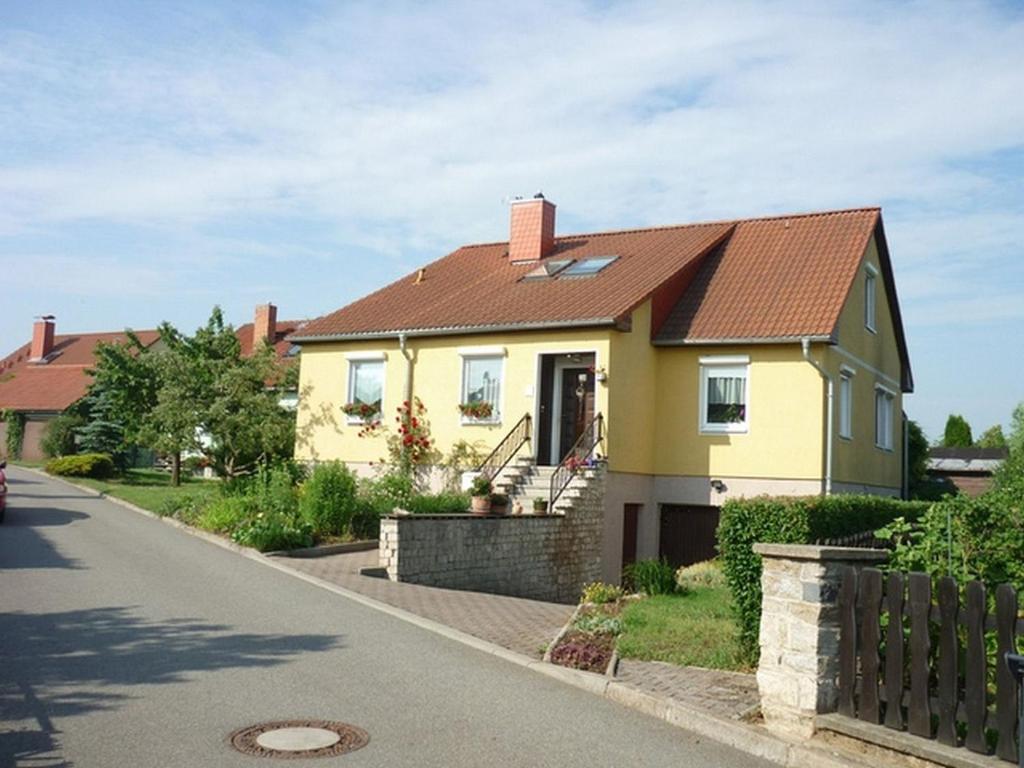 una casa amarilla con techo marrón en una calle en Ferienwohnung Katzmann, en Kromsdorf