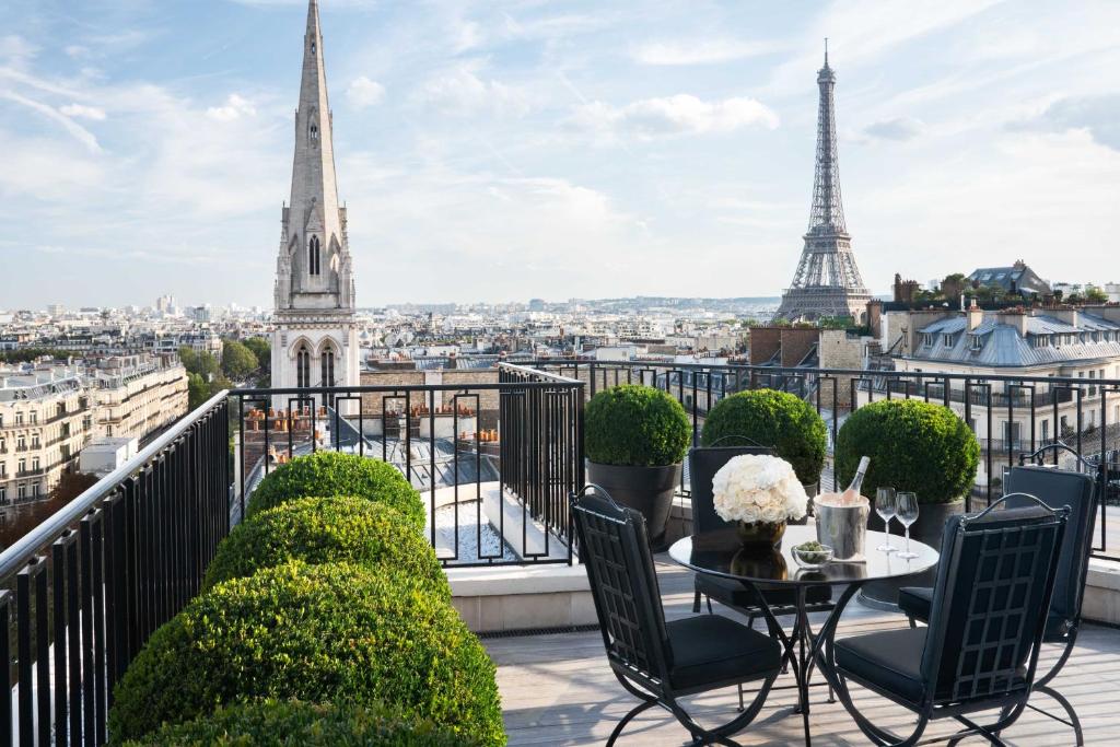 balkon ze stołem i krzesłami oraz wieżą Eiffel w obiekcie Four Seasons Hotel George V Paris w Paryżu