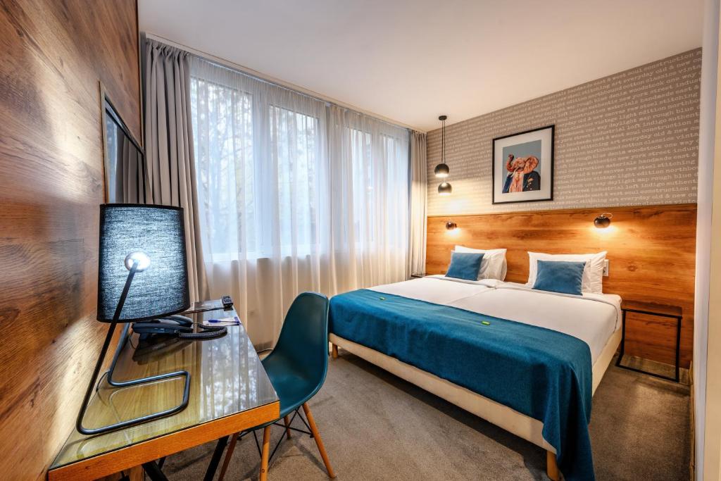 um quarto de hotel com uma cama e uma secretária com uma televisão em Roombach Hotel Budapest Center em Budapeste