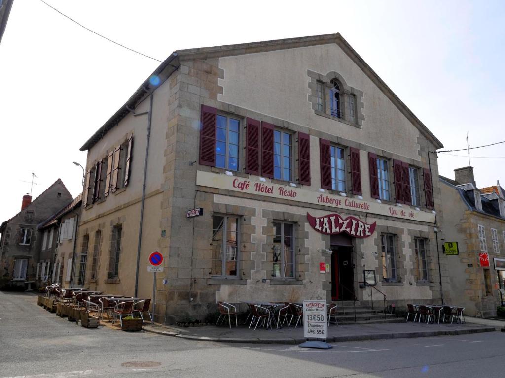 stary budynek ze stołami i krzesłami przed nim w obiekcie L'Alzire - Auberge Culturelle w mieście Jarnages