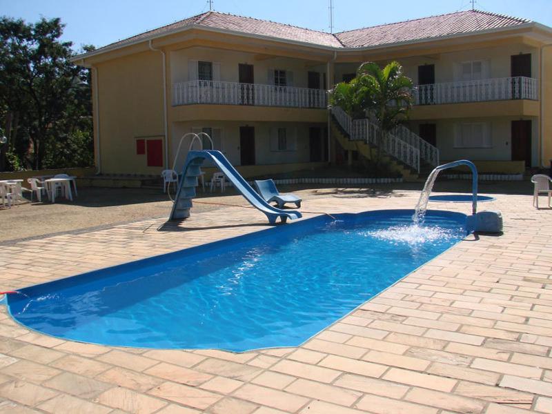 a pool with a slide in front of a house at Hotel Villagio D'Italia in Vinhedo