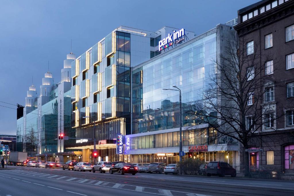 a large glass building with cars parked in front of it at Park Inn by Radisson Central Tallinn in Tallinn