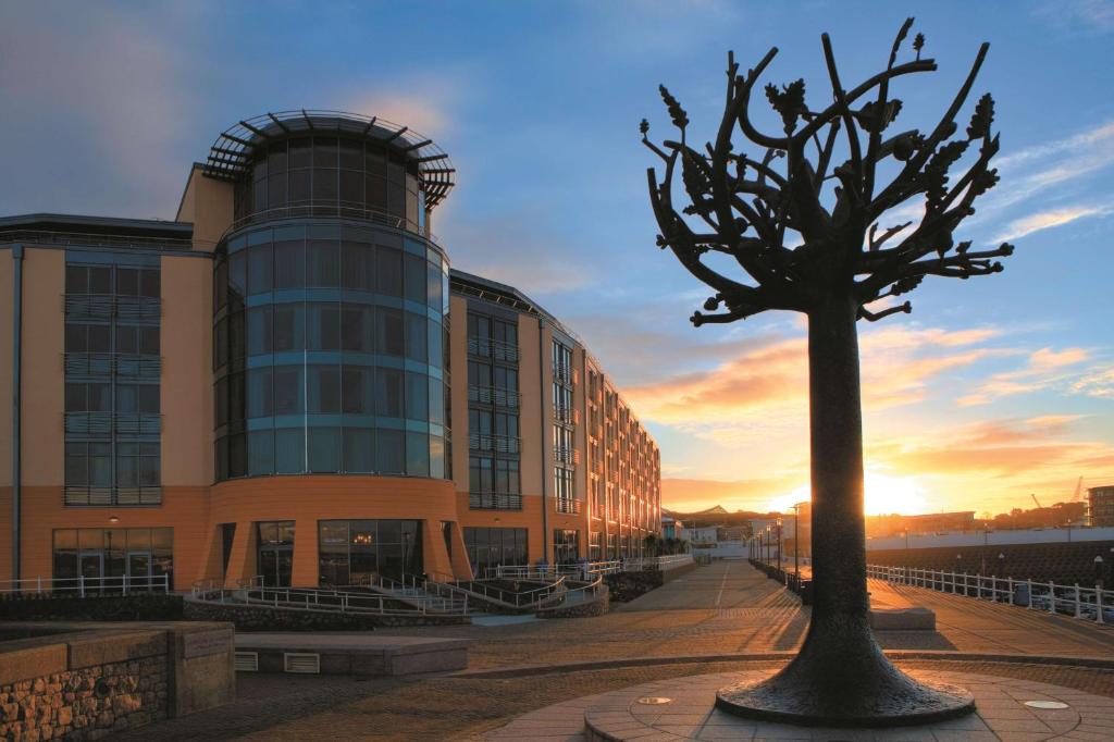 a building with a tree in front of it at Radisson Blu Waterfront Hotel, Jersey in Saint Helier Jersey
