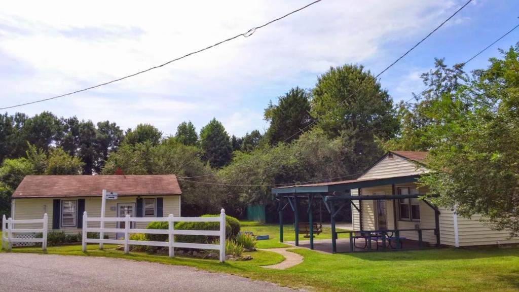 a house with a white fence and a playground at Anvil Campground in Williamsburg