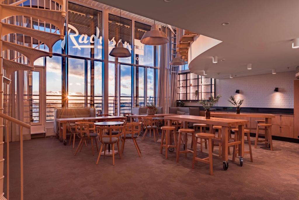 a restaurant with tables and chairs and large windows at Radisson Blu Seaside Hotel, Helsinki in Helsinki
