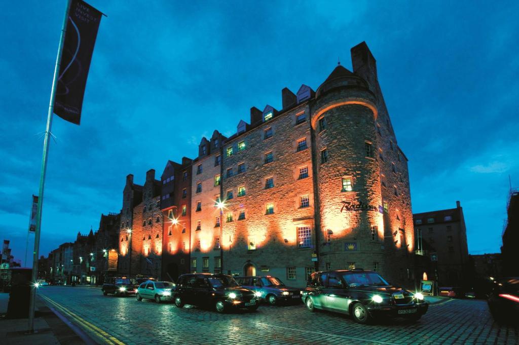 um grupo de carros estacionados em frente a um grande edifício em Radisson Blu Hotel, Edinburgh City Centre em Edinburgo