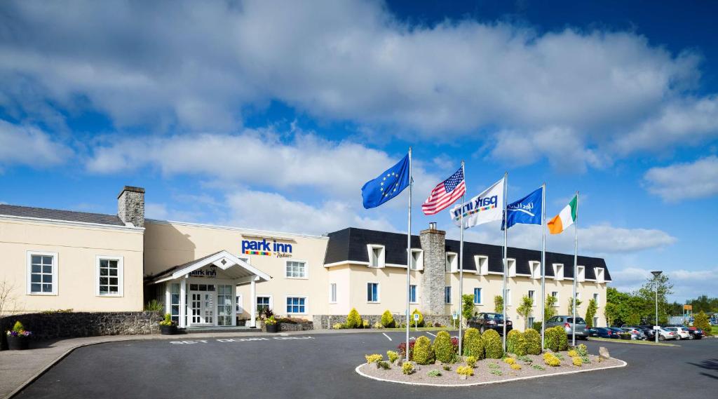 a hotel with flags in front of a building at Park Inn by Radisson Shannon Airport in Shannon