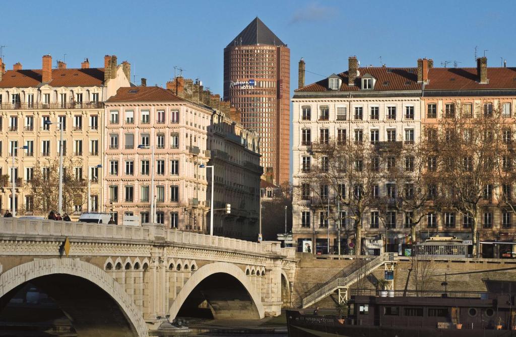 un ponte su un fiume in una città con edifici di Radisson Blu Hotel, Lyon a Lione