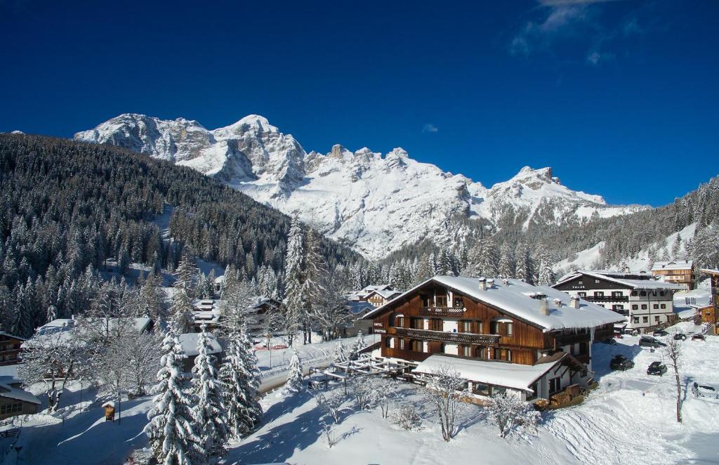 a ski lodge with snow covered mountains in the background at Hotel Sporting in Val di Zoldo