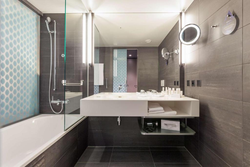 y baño con lavabo, bañera y ducha. en Radisson Blu Hotel, Lucerne, en Lucerna