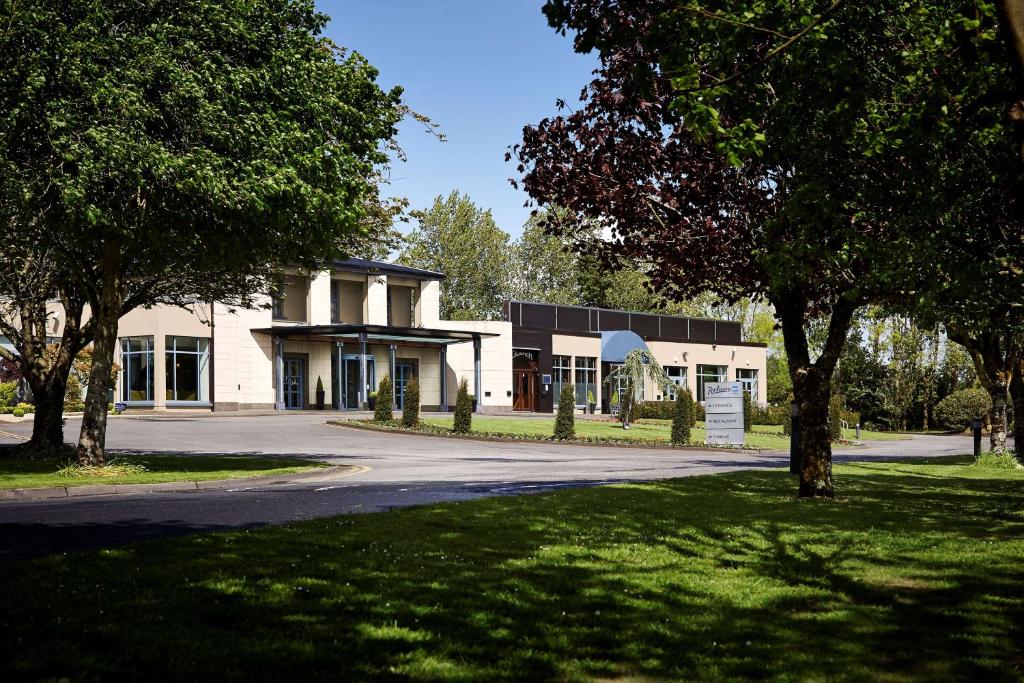 ein weißes Gebäude mit Bäumen vor einer Straße in der Unterkunft Radisson BLU Hotel and Spa, Limerick in Limerick