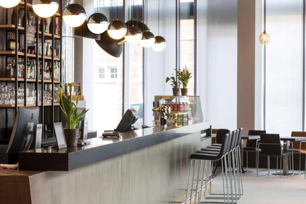 a bar in a restaurant with chairs and lights at Park Inn by Radisson Leuven in Leuven