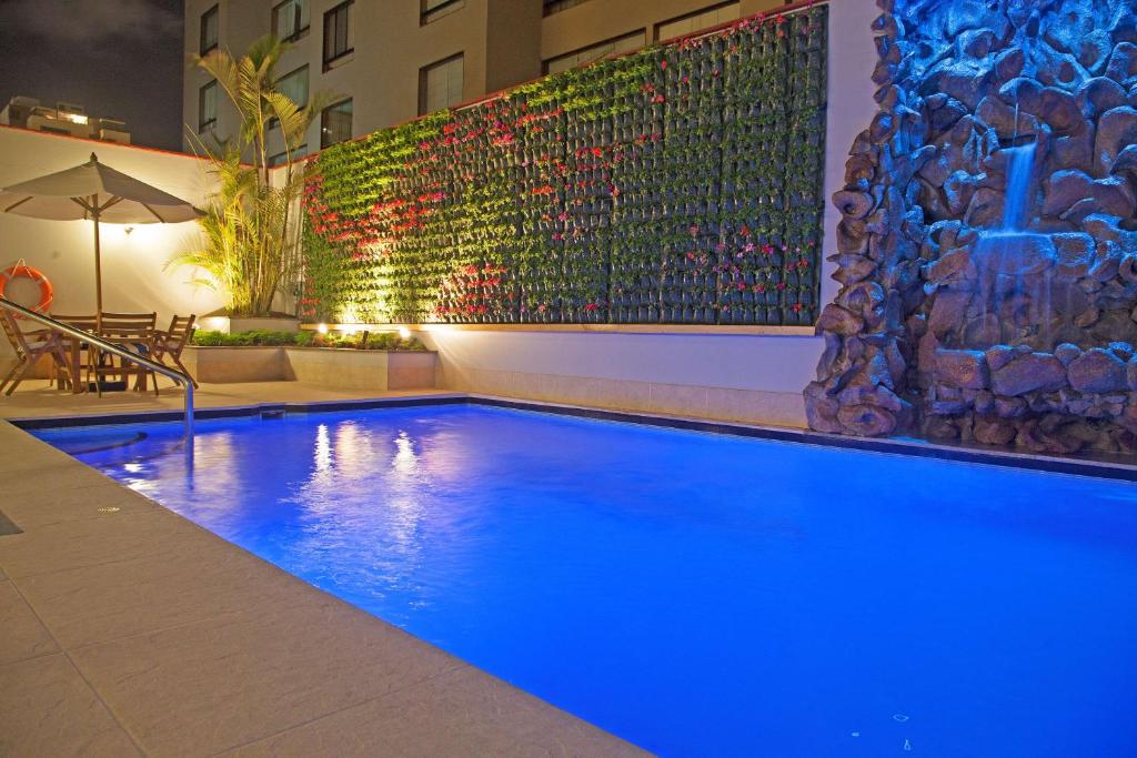 ein großer blauer Pool mit einem Gemälde an der Wand in der Unterkunft Radisson San Isidro Hotel & Suites in Lima