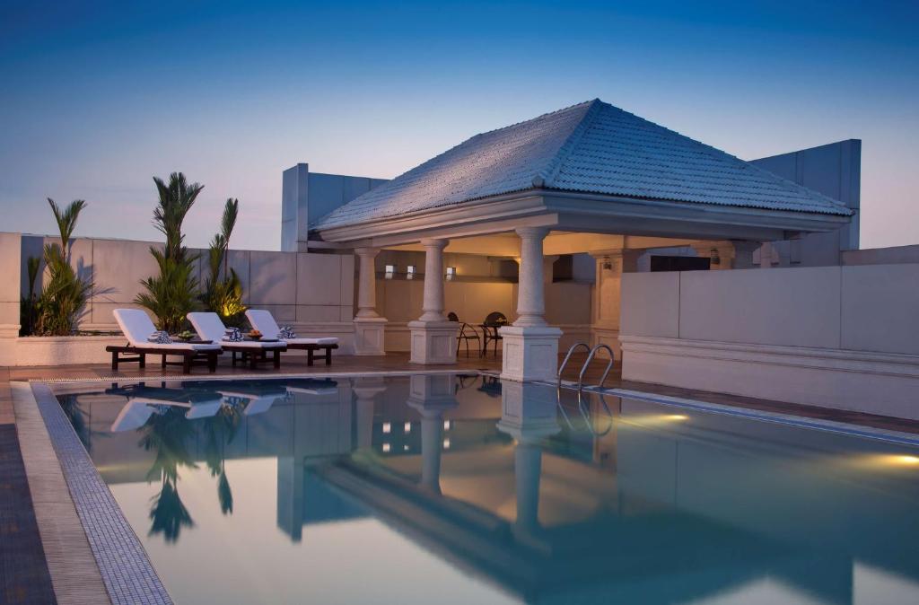 a swimming pool with two chairs next to a building at Radisson Blu Kochi in Cochin