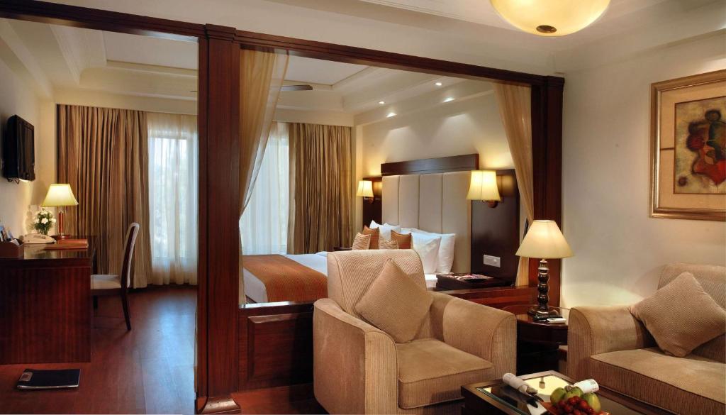 um quarto de hotel com uma cama, um sofá e cadeiras em Park Plaza Jodhpur em Jodhpur