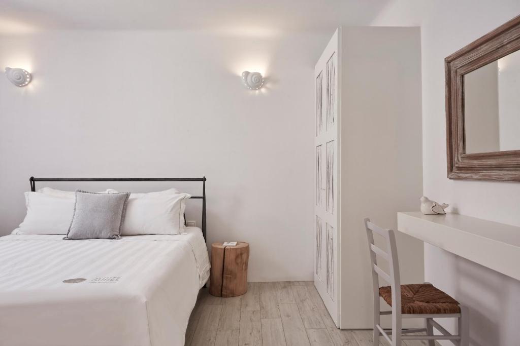 een witte slaapkamer met een bed en een spiegel bij Dunes Apartment Part Of White Dunes Luxury Boutique Hotel in Santa Maria
