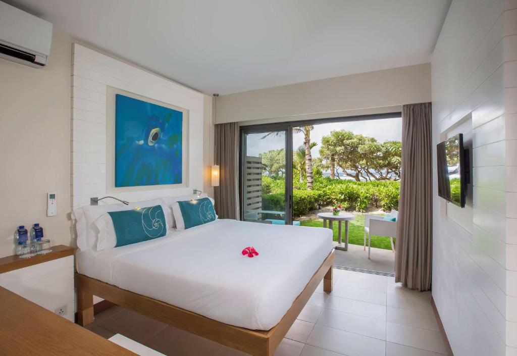 a bedroom with a large white bed and a balcony at Radisson Blu Poste Lafayette Resort & Spa (Adults Only) in Poste Lafayette