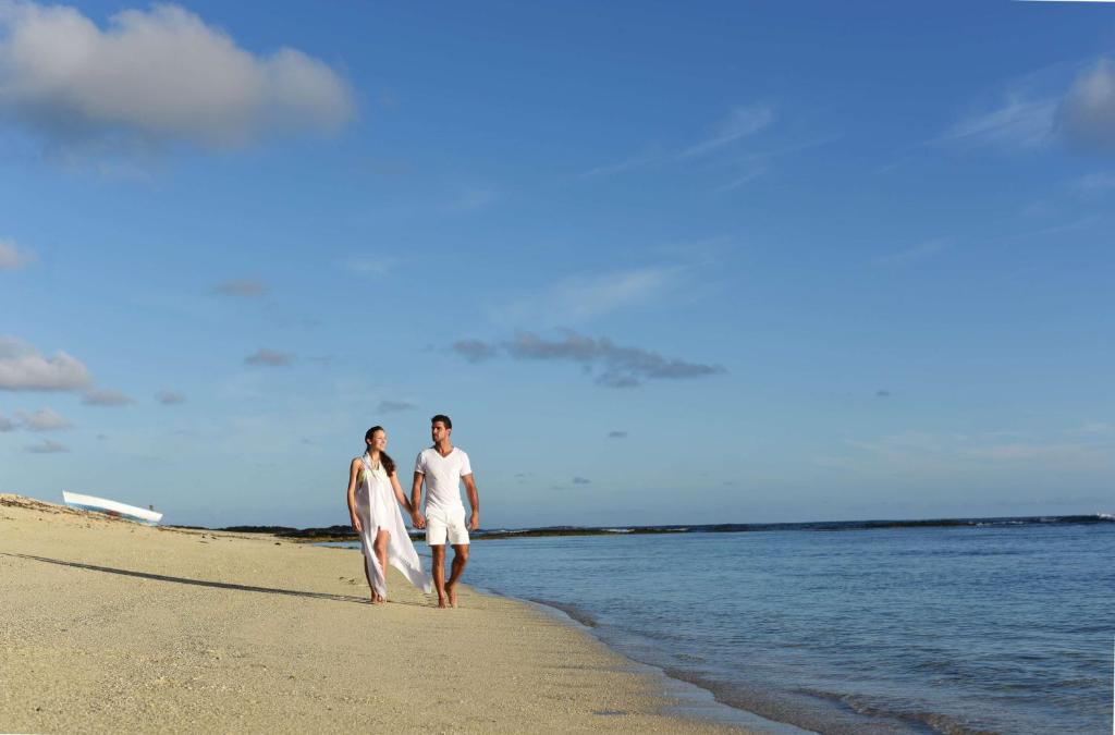 two people walking on the beach with their surfboards at Radisson Blu Poste Lafayette Resort & Spa (Adults Only) in Poste Lafayette