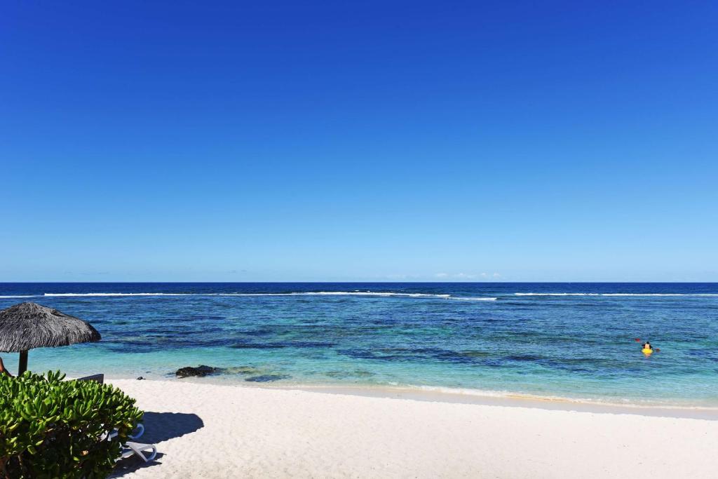 a beach with an umbrella and the ocean at Radisson Blu Poste Lafayette Resort & Spa (Adults Only) in Poste Lafayette