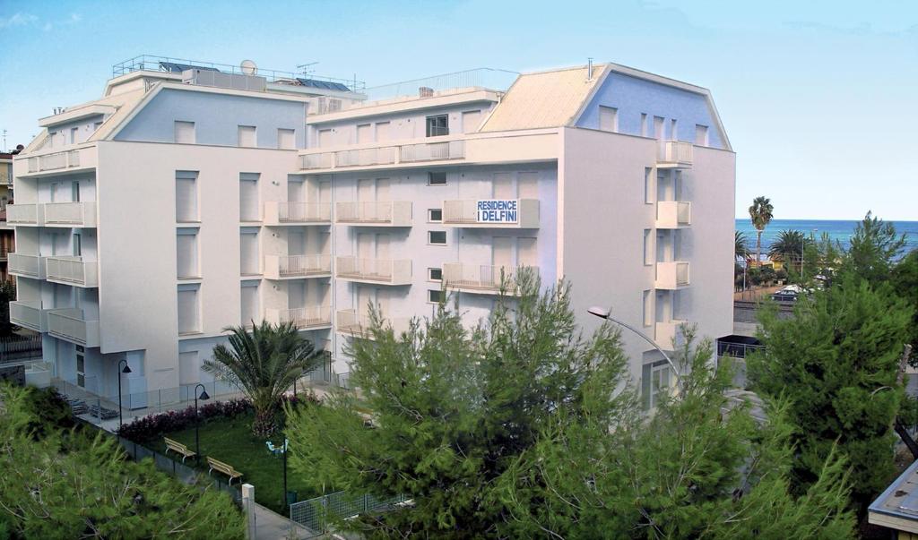 duży biały budynek z drzewami przed nim w obiekcie Residence I Delfini w mieście Cupra Marittima