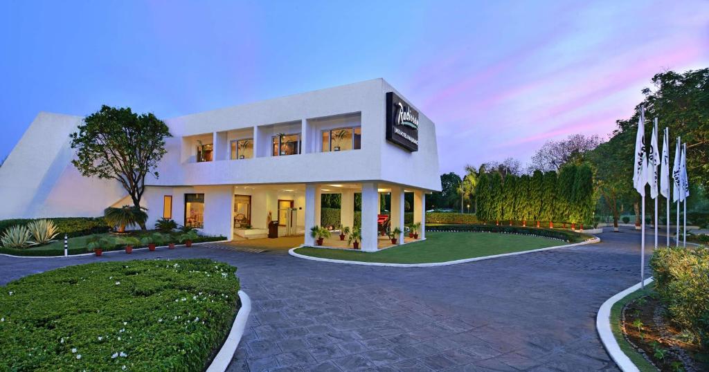 a large white house with a driveway at Radisson Jass Hotel, Khajuraho in Khajurāho