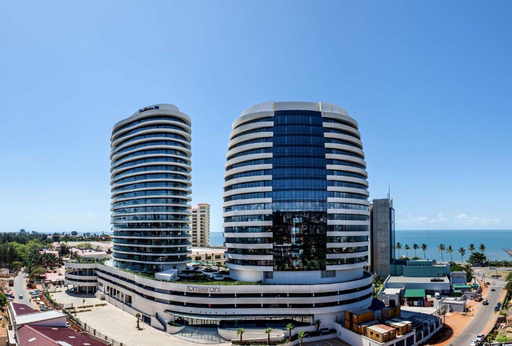 twee hoge gebouwen in een stad met de oceaan bij Radisson Blu Hotel & Residence Maputo in Maputo