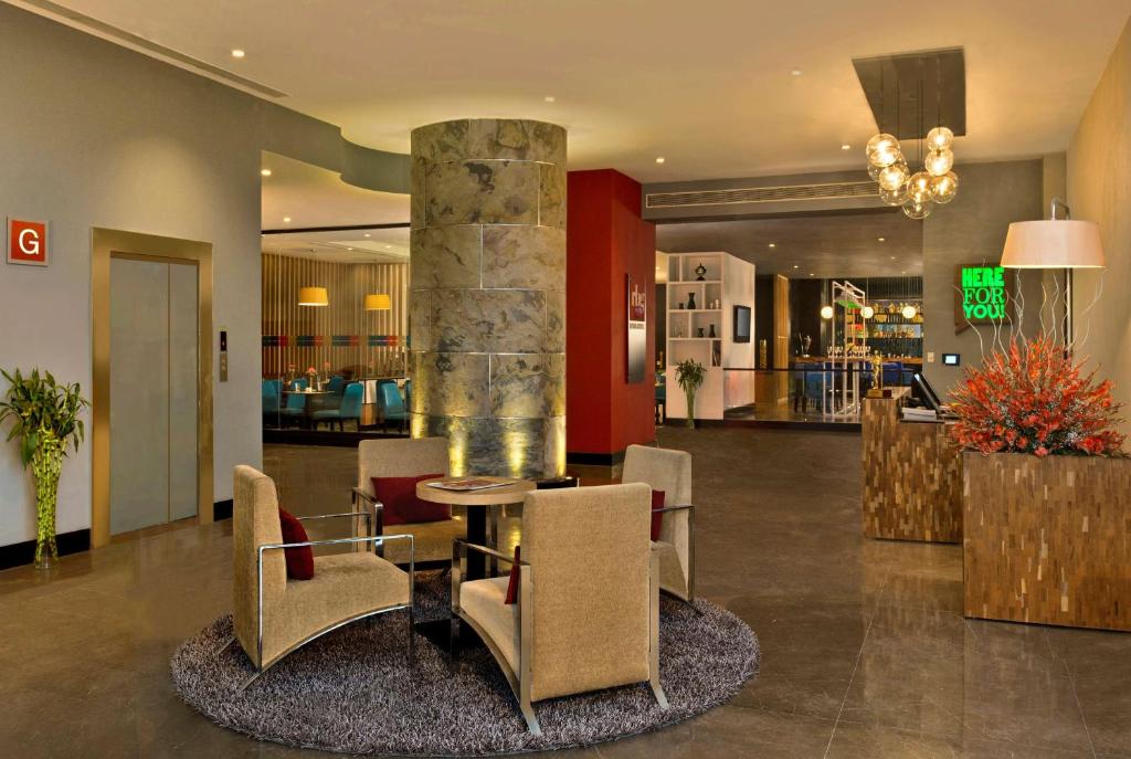 un vestíbulo con mesa, sillas y un pilar en Park Inn by Radisson New Delhi IP Extension, en Nueva Delhi