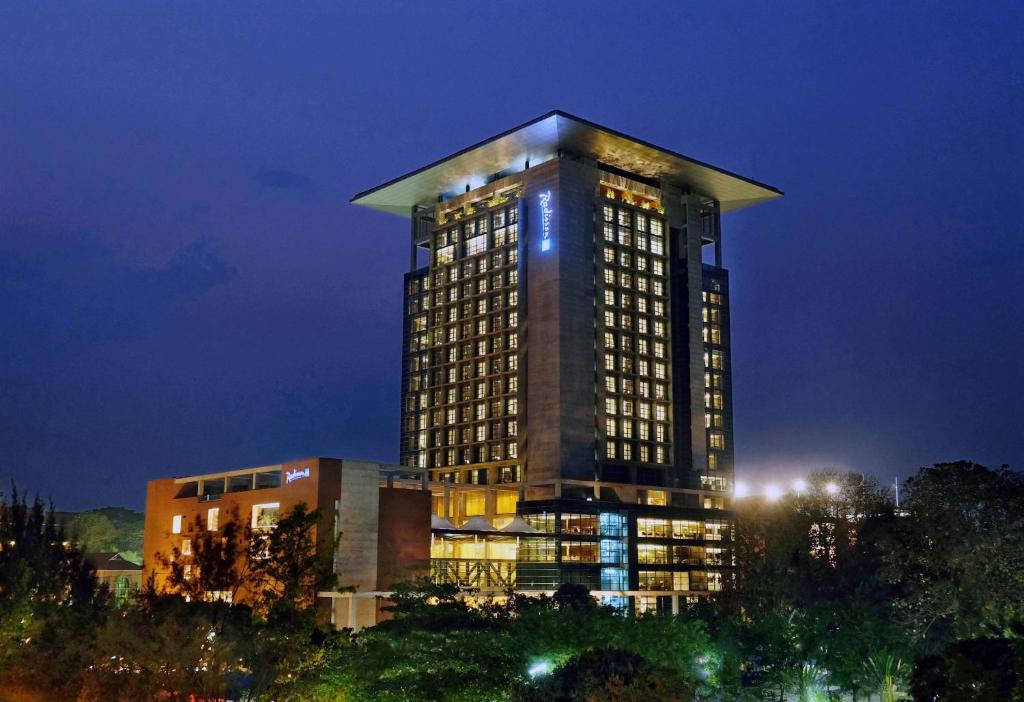 a tall building with lights on it at night at Radisson Blu Chattogram Bay View in Chittagong