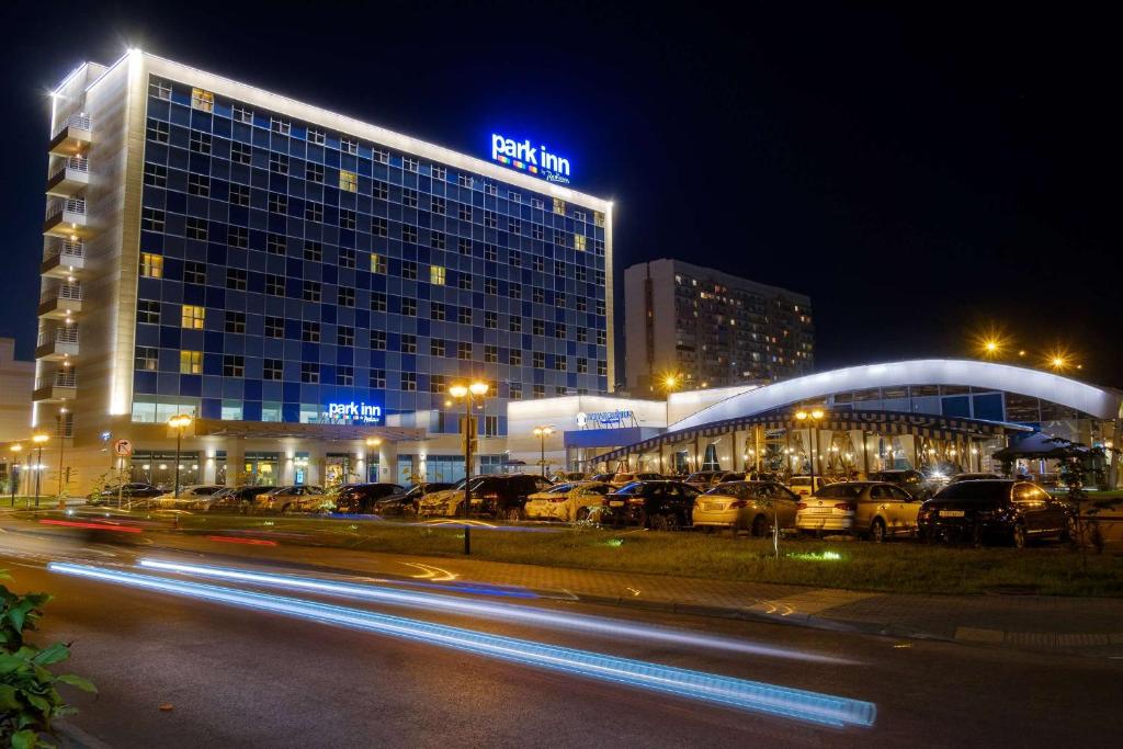 un edificio con coches estacionados en un estacionamiento por la noche en Park Inn by Radisson Novokuznetsk, en Novokuznetsk