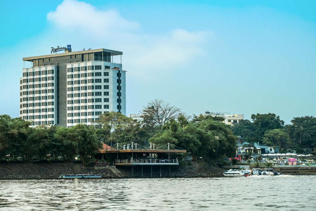 a large building next to a body of water at Radisson Blu M'Bamou Palace Hotel, Brazzaville in Brazzaville
