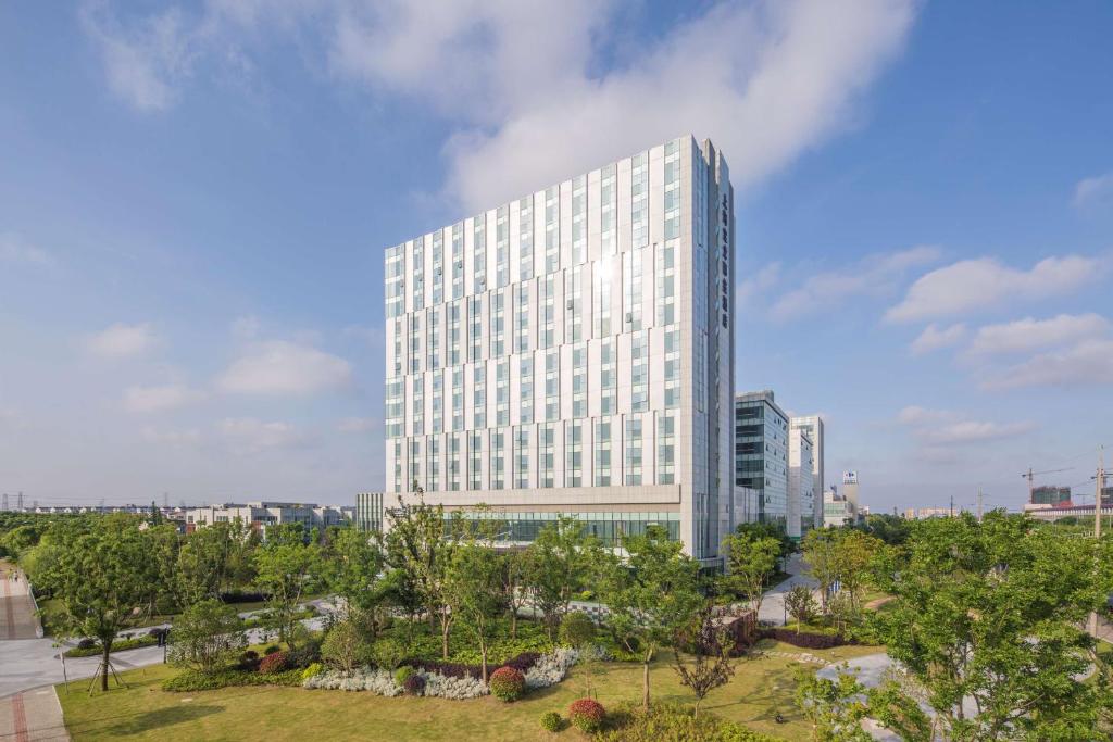 een hoog wit gebouw met bomen ervoor bij Radisson Blu Shanghai Pudong Jinqiao in Shanghai