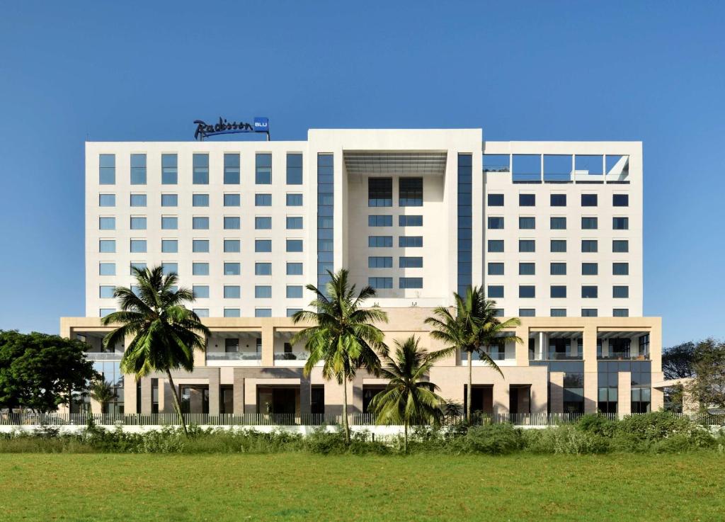 a large white building with palm trees in front of it at Radisson Blu Coimbatore in Coimbatore