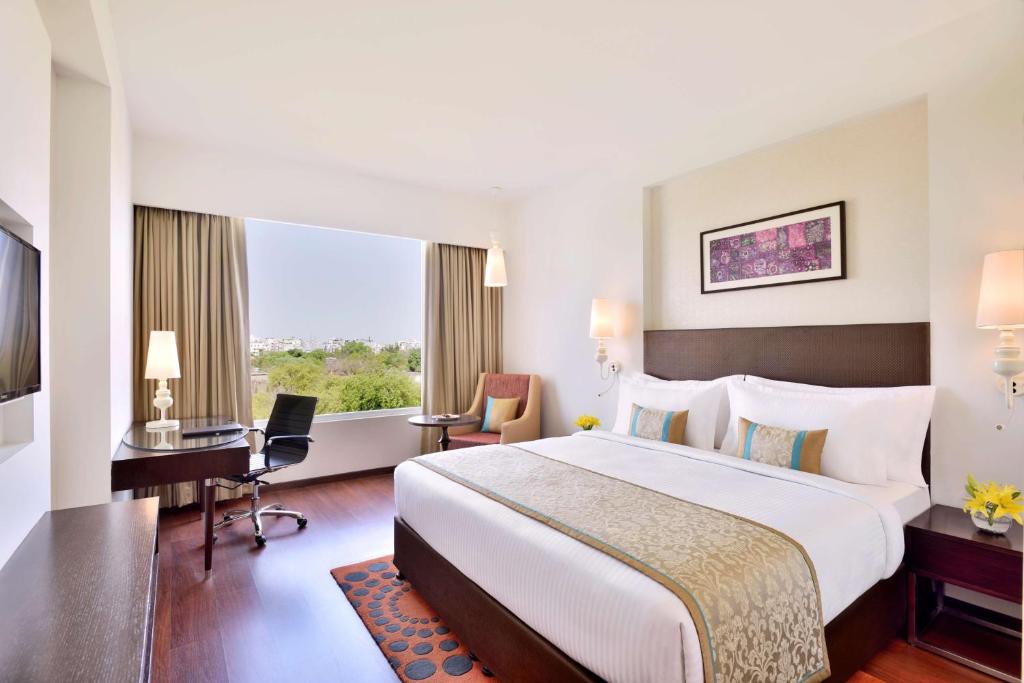 a hotel room with a large bed and a desk at Country Inn & Suites by Radisson Kota in Kota