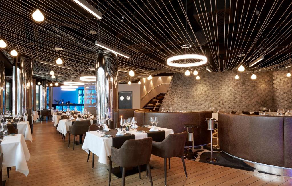 un restaurante con mesas y sillas blancas y una escalera en Radisson Blu Resort Swinoujscie, en Świnoujście