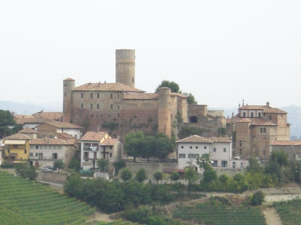 a village with a large castle on a hill at Arco Dei Nobili in Monforte dʼAlba