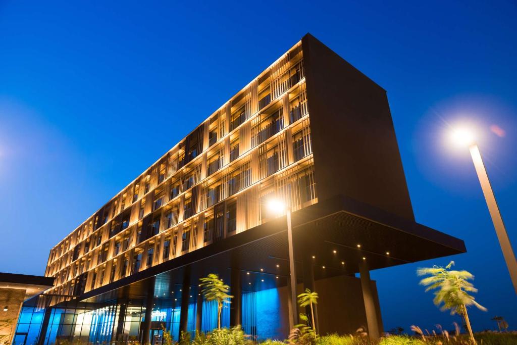 un bâtiment noir avec des palmiers et un éclairage de rue dans l'établissement Radisson Hotel Dakar Diamniadio, à Dakar