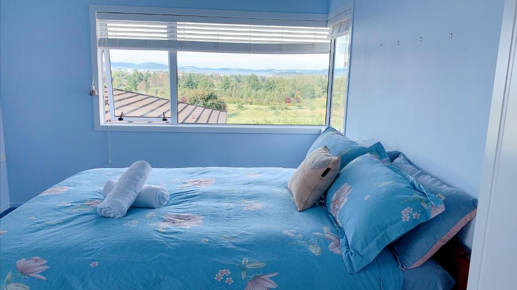 Dormitorio azul con cama y ventana en Panoramic View Apartment Without a Kitchen en Rotorua