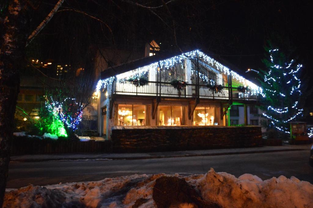 une maison décorée avec des lumières de Noël et un arbre de Noël dans l'établissement Hôtel Restaurant La Tourmaline, à Aime La Plagne