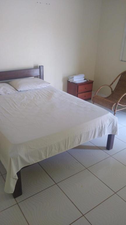 a bed in a room with a chair and a table at Pousada Potiguara Irapuan in Iranduba