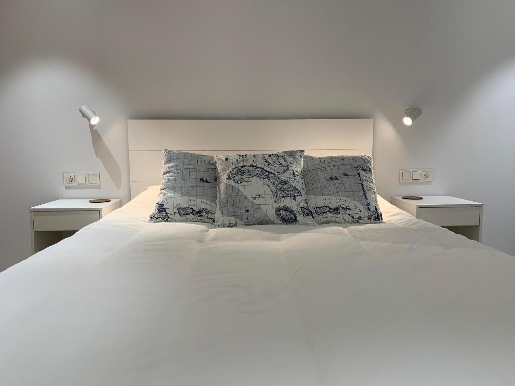 ein Schlafzimmer mit einem weißen Bett und zwei Nachttischen in der Unterkunft Aldamar apartamentua PARKING INCLUIDO in Getaria