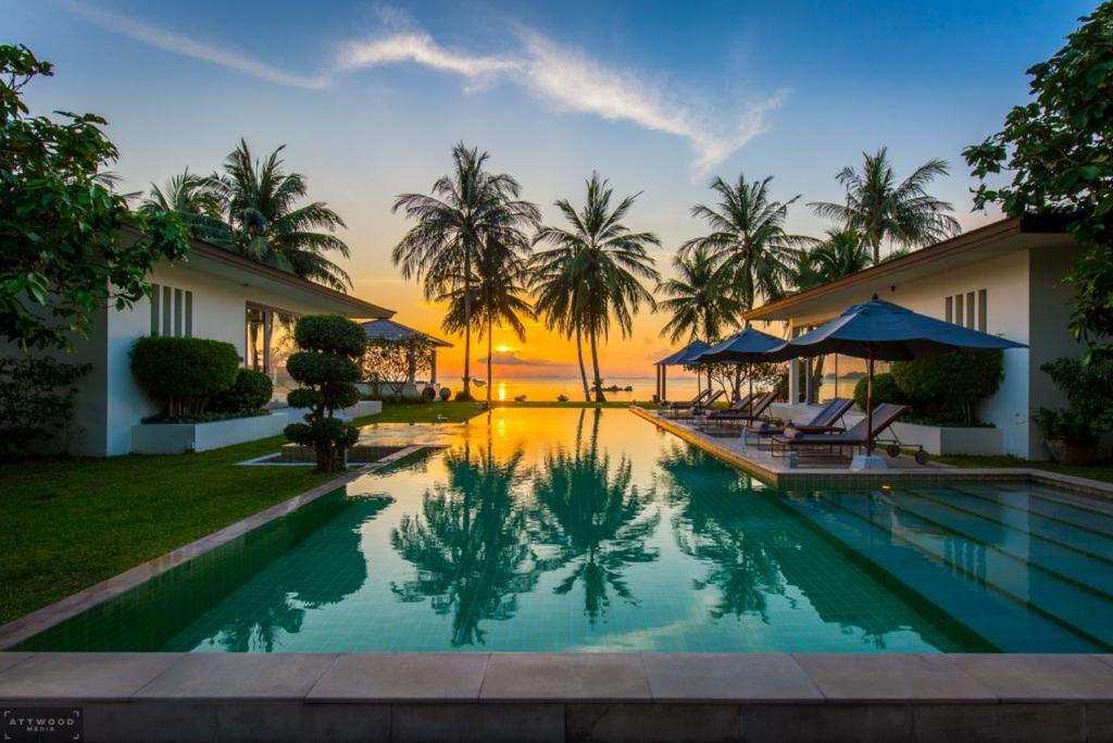 a villa with a swimming pool and palm trees at Baan Asan in Taling Ngam Beach