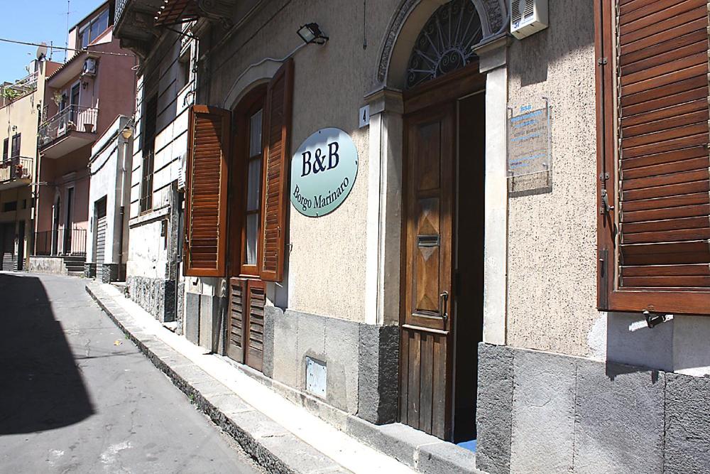 a building with a sign on the side of a street at Borgo Marinaro in Aci Castello